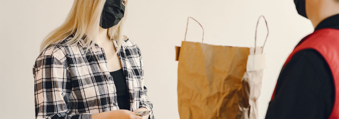 man handing bag of groceries to woman